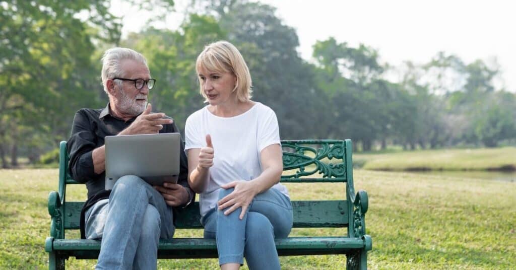 Understanding Medicare webinar post of a 65 year old couple discussing webinar on a park bench.