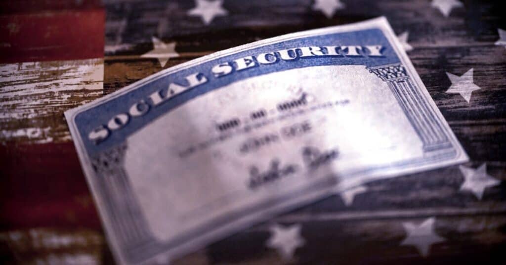 Image of a social security card on a brown table. The image is slightly blurred and is used for the purpose of representing social security and retirement.